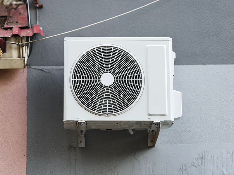 New outdoor heat pump unit mounted to outside of a house.
