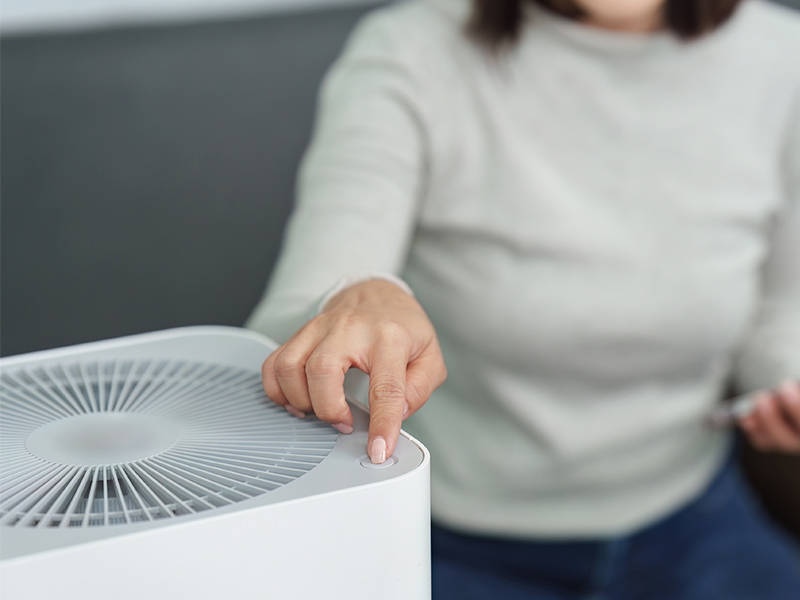 Woman pressing a button on an air purifier.