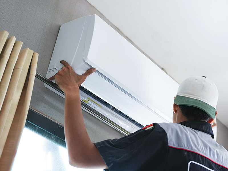 HVAC technician installing a wall mounted HVAC unit.
